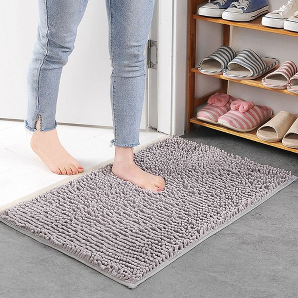 Person stepping onto a gray rug with shoes and slippers on a shelf in the background.