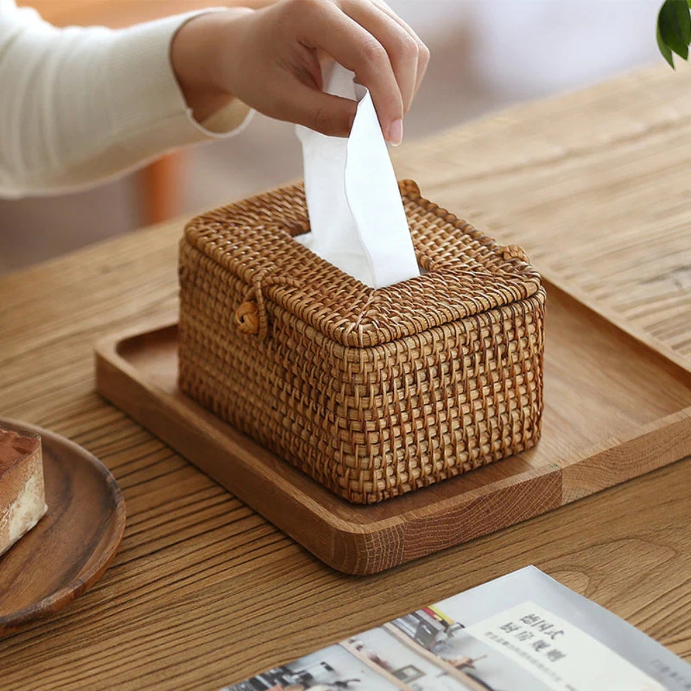 Woven tissue box on a wooden tray with a hand reaching for a tissue.