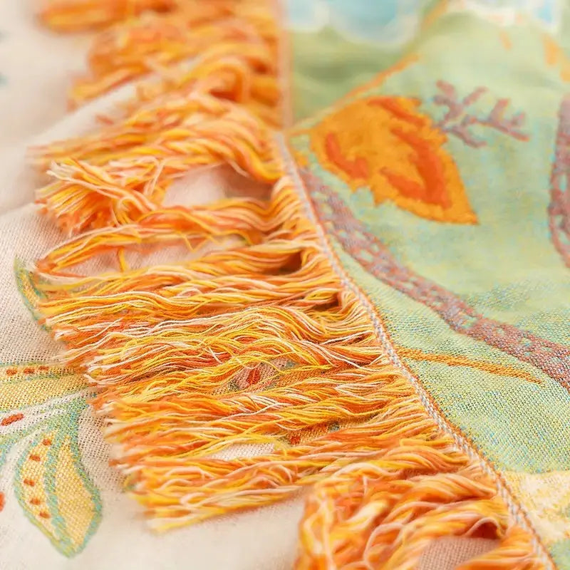 Close-up of a decorative fabric with orange fringes and floral patterns.