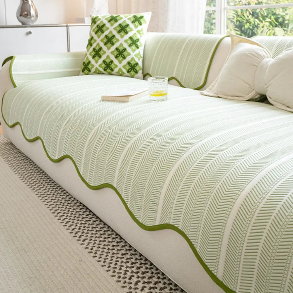 Green and white patterned sofa cover on a couch with decorative pillows.