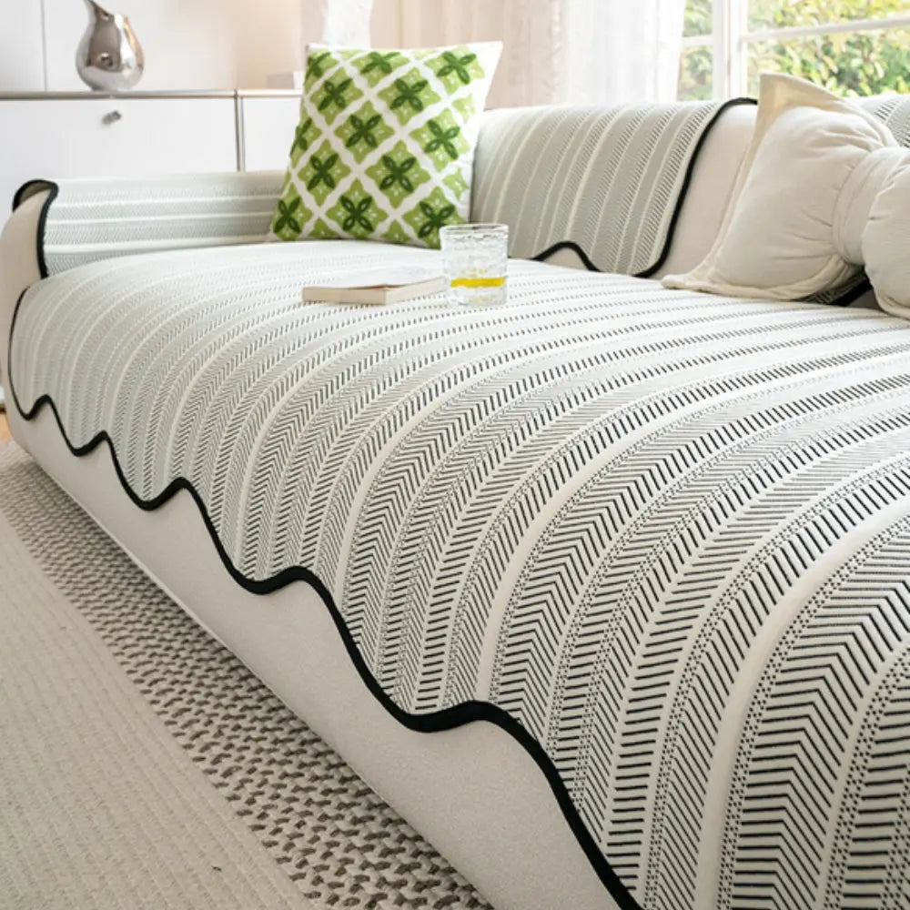 Patterned blanket on a bed with a pillow and lamp in the background