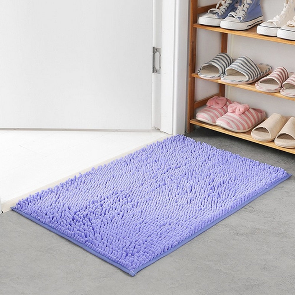 Purple rug on a gray floor with a wooden shelf holding shoes and slippers.