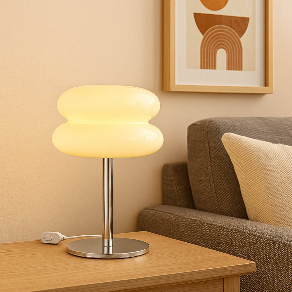 Table lamp on a wooden side table with a sofa and framed artwork in the background