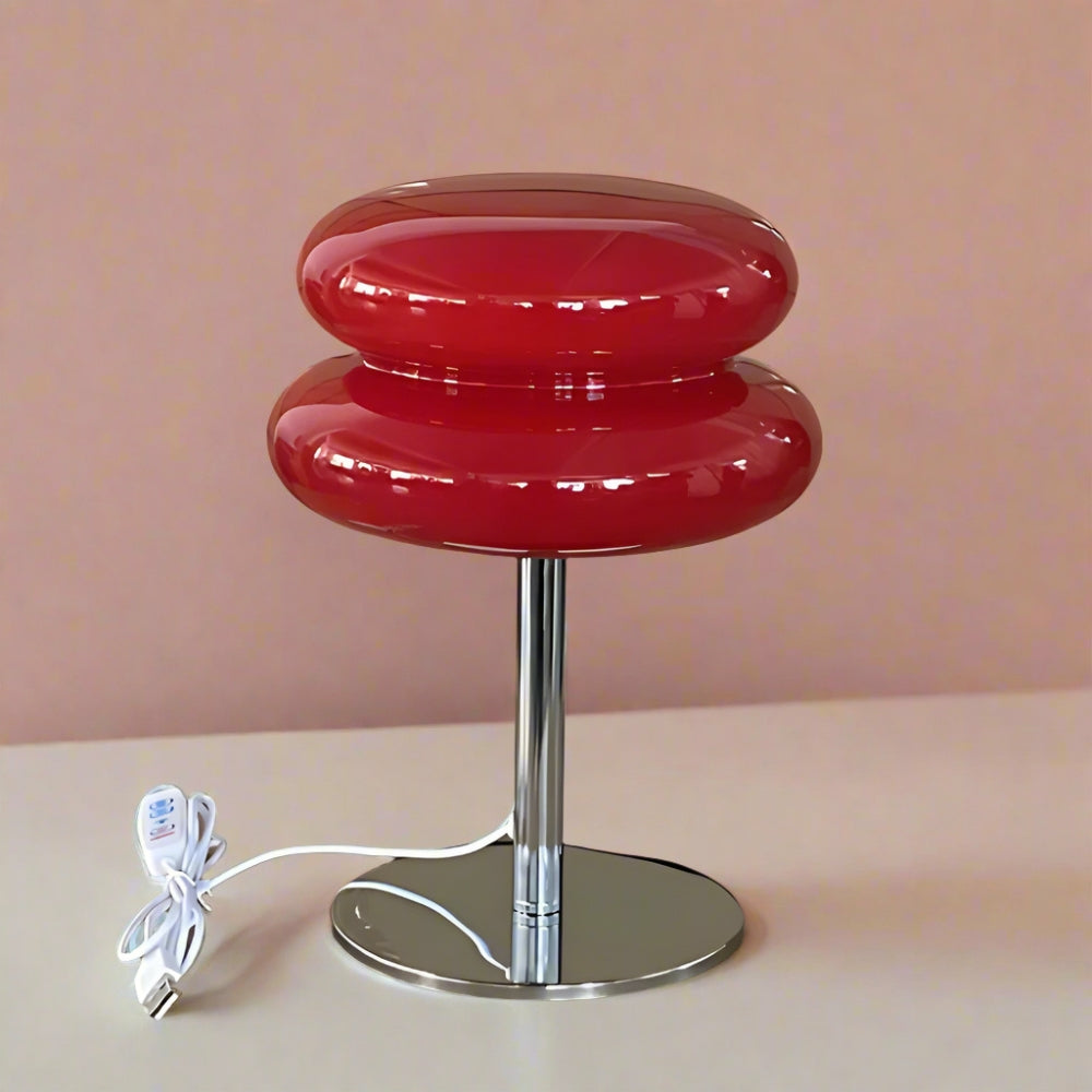 Red lamp with a white cord on a beige surface against a pink wall