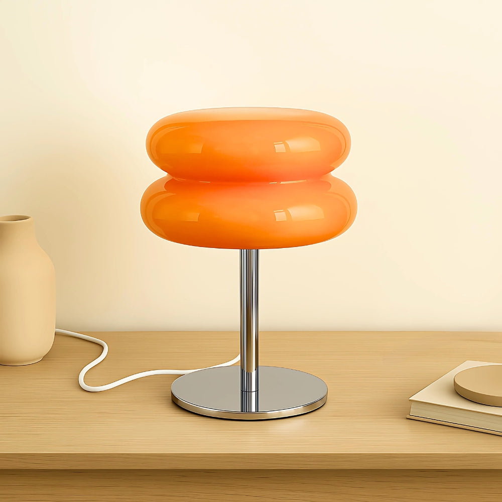 Orange table lamp with a metallic base on a wooden surface.