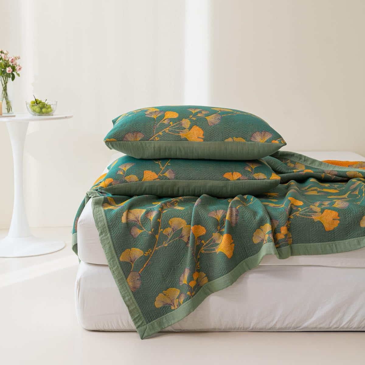 Green floral-patterned blanket and pillows on a white sofa with a neutral background