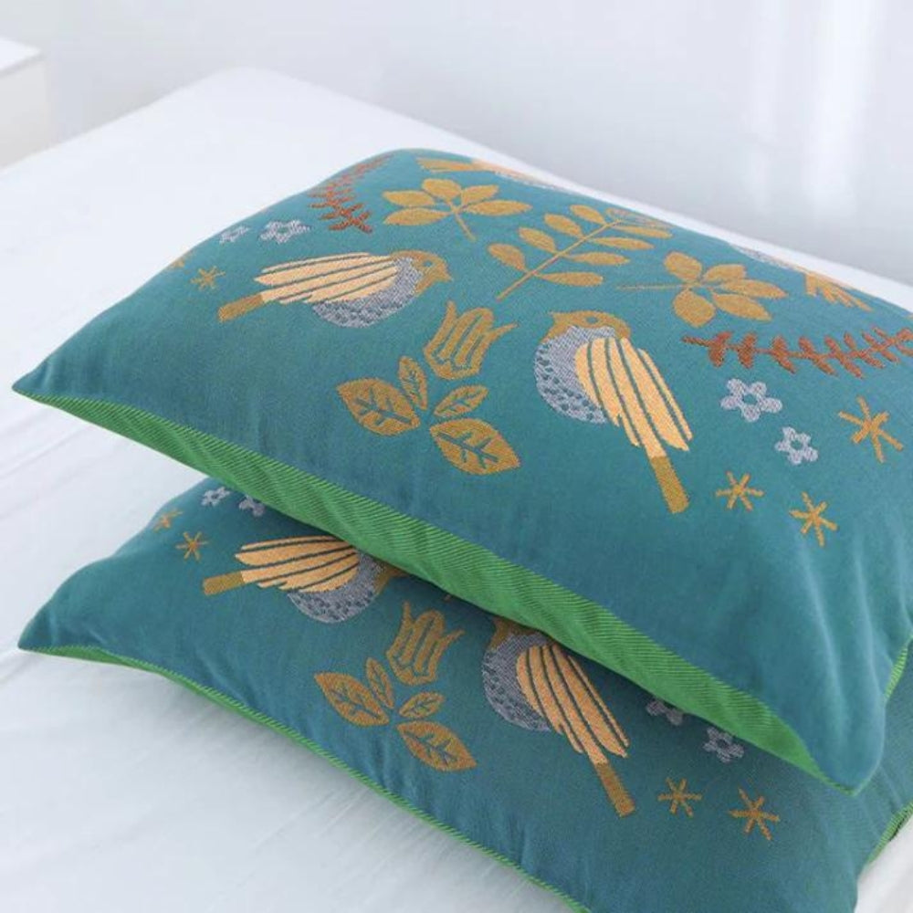 Teal pillow with floral patterns on a white background