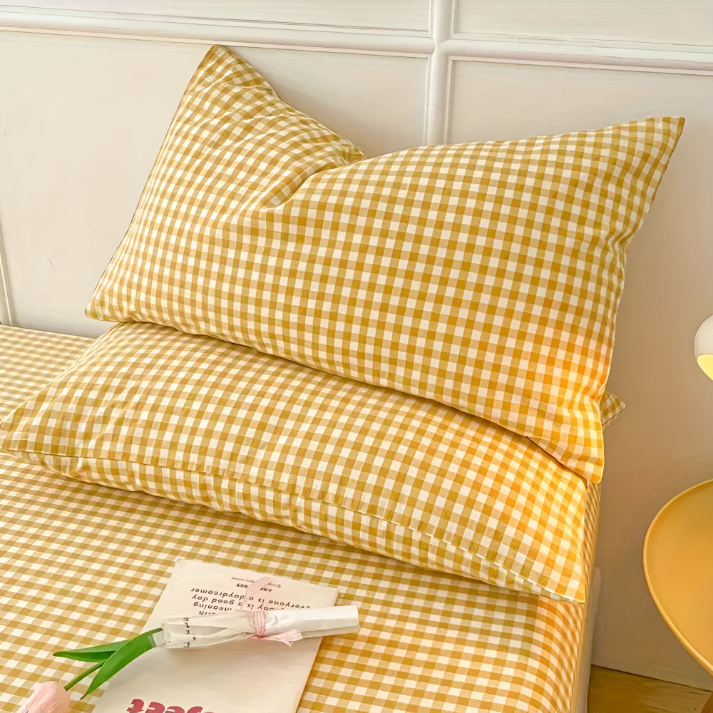 Yellow checkered bedding set on a bed with a lamp in the background