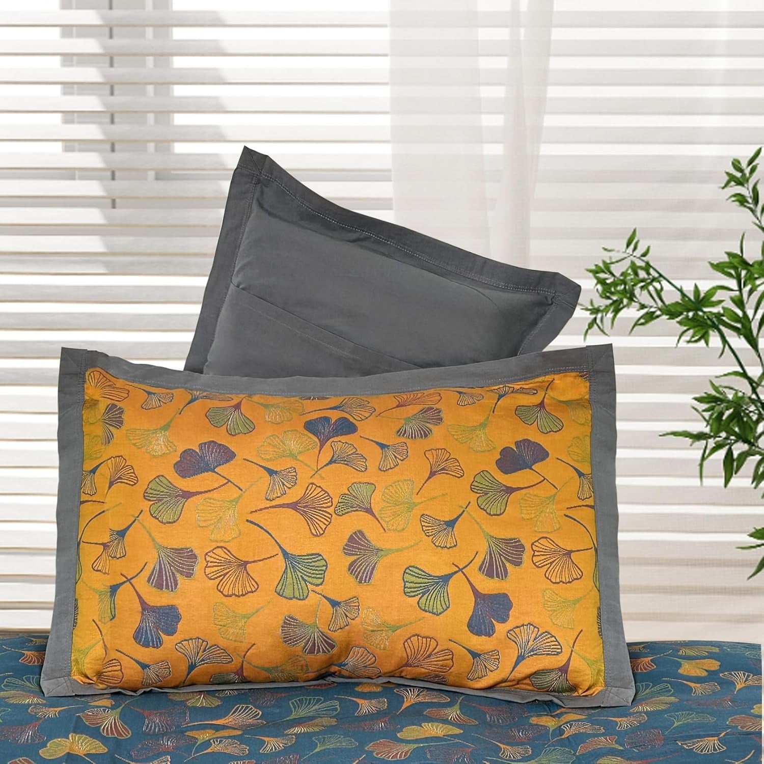 Decorative pillows with floral pattern on a bed with white blinds in the background