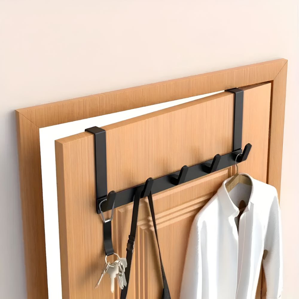 Wooden door organizer with black hooks holding a coat and keys on a wooden door.