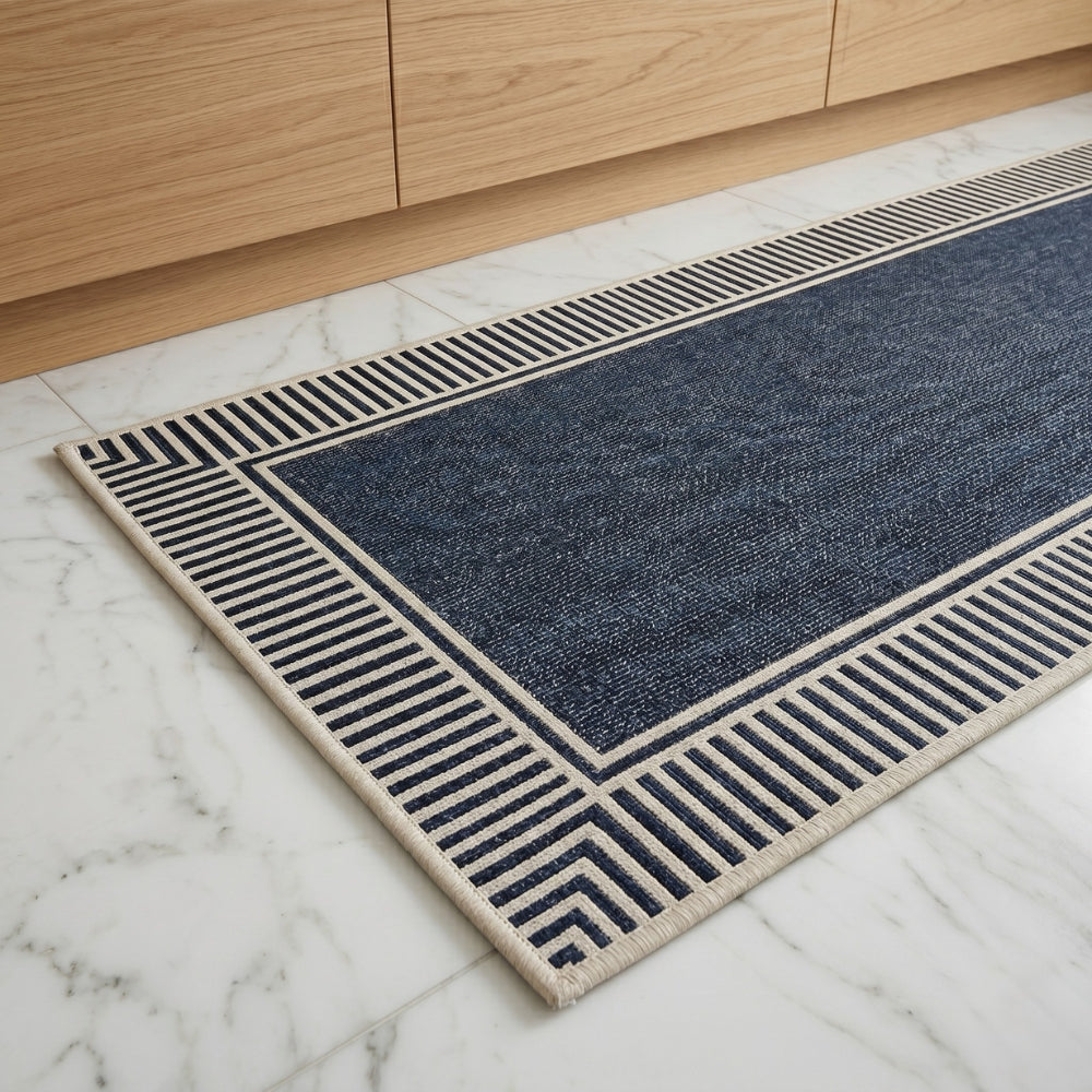 Blue and beige patterned rug on a marble floor with wooden cabinets in the background