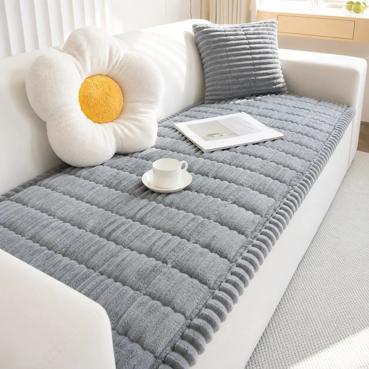 Gray textured sofa cover on a white sofa with decorative pillows and a cup.