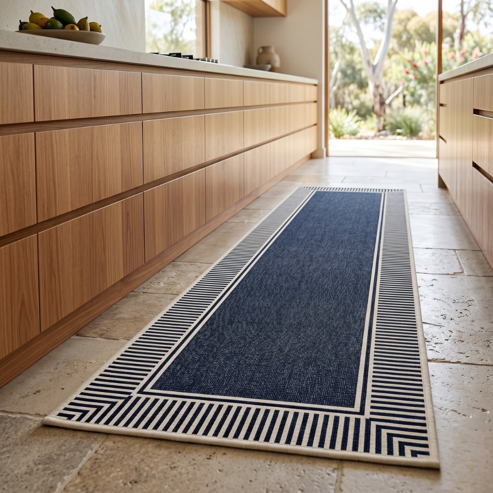 Navy blue runner rug with geometric pattern on a stone floor in a kitchen.