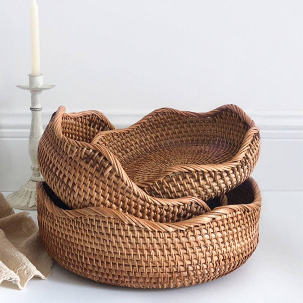 Stack of woven baskets on a white surface with a candle in the background
